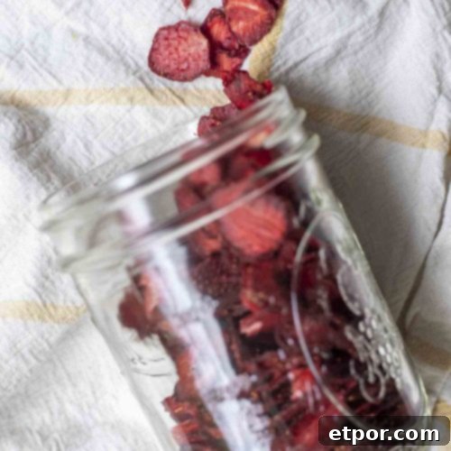 Mastering Homemade Dehydrated Strawberries 13 overhead photo of dried strawberries in a mason jar tipped over and sprinkled out on a white and yellow towel