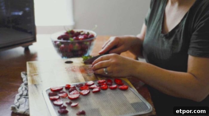 Mastering Homemade Dehydrated Strawberries 7 woman slicing strawberries and placing them on a dehydrator pan.