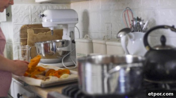 A woman's hands carefully scooping the soft, roasted flesh of butternut squash from the baking sheet directly into a large pot, ready to be transformed into soup.
