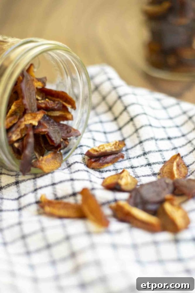 Dried plums spilling out of a mason jar on a white and black checked towel.