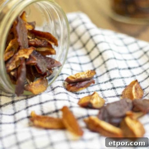Dried plums spilling out of a mason jar on a white and black checked towel