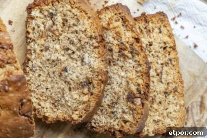 Three slices of sourdough apple bread on a wood cutting board, showcasing the delicious caramelized apple chunks throughout the bread.