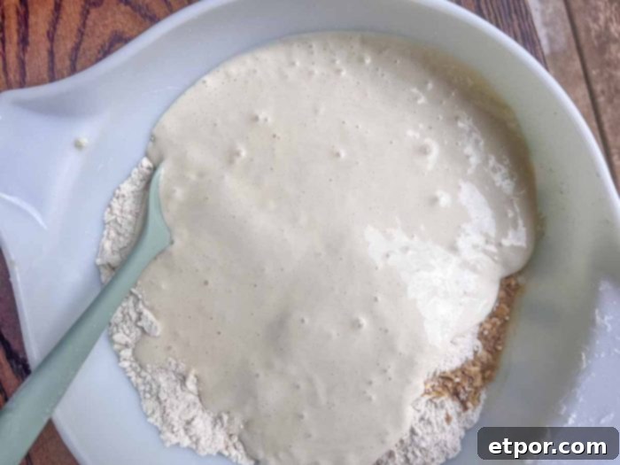 Sourdough starter and vanilla extract being added to a flour and butter mixture in a white bowl, signaling the next step in dough preparation.