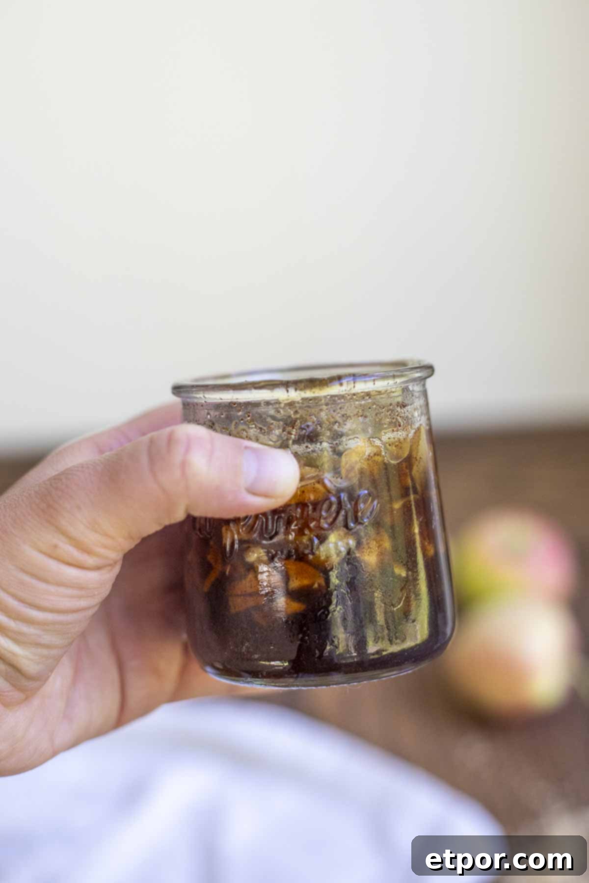 hand holding a small jar of apple syrup.