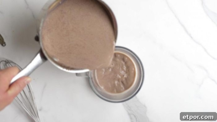 pouring gingerbread hot chocolate into a glass mug.