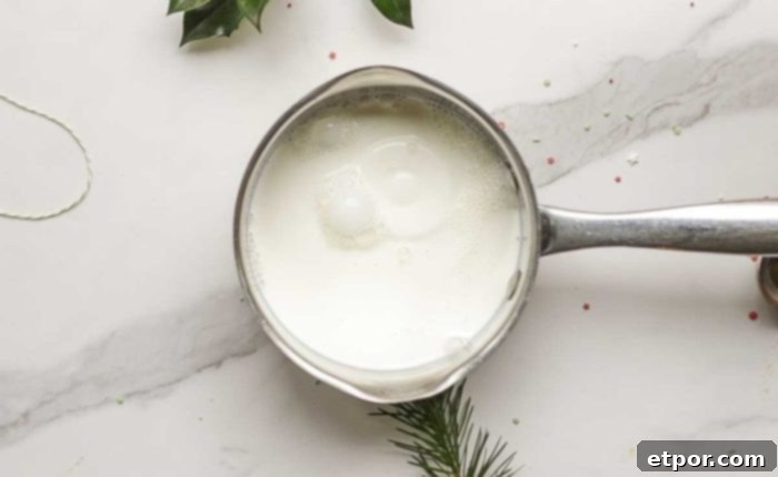 Whip Up Homemade Gingerbread Coffee Creamer 6 half and half in a saucepan on a marble countertop