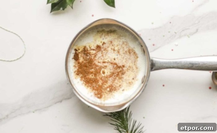 Whip Up Homemade Gingerbread Coffee Creamer 7 half and half, spices, vanilla, and molasses in a saucepan on a white marble countertop