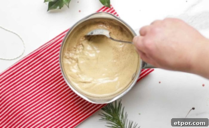 Whip Up Homemade Gingerbread Coffee Creamer 8 stirring coffee creamer on a red stripped towel on a marble countertop
