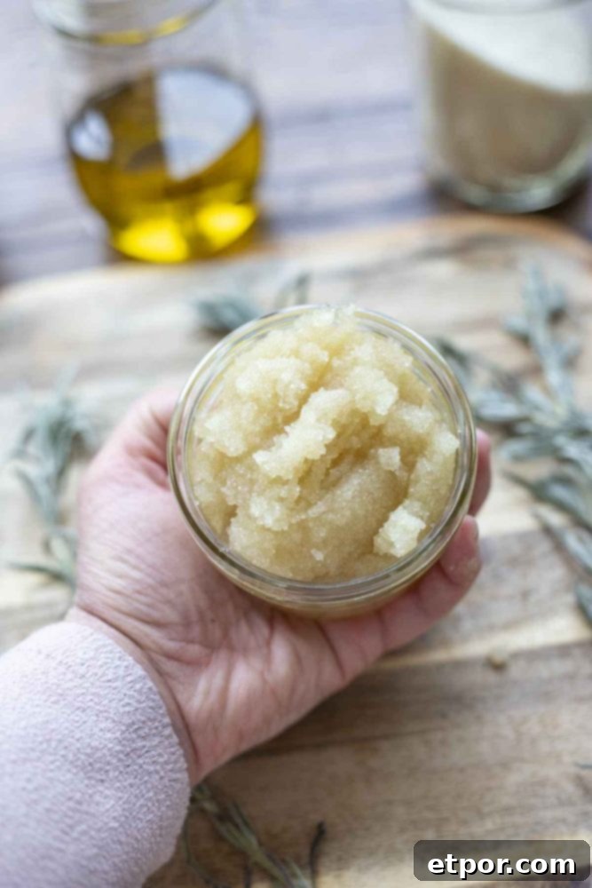 hand holding a jar of peppermint sugar sugar scrub over a wood cutting board with dried lavender spread on the board