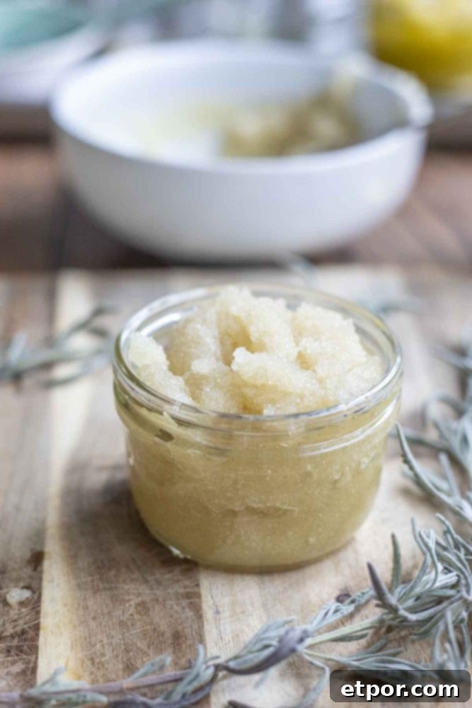jar of peppermint sugar scrub on a wood cutting board with sprigs of fresh lavender. A bowl of the remaining scrub is in the background