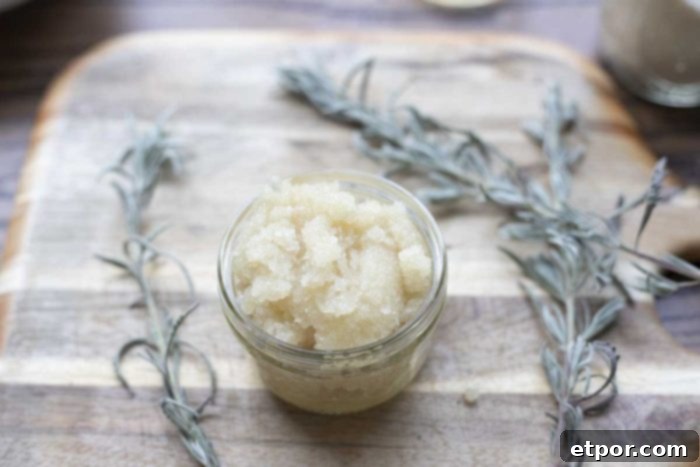 small jar of sugar scrub on a wood cutting board surrounded by fresh sprigs of lavender