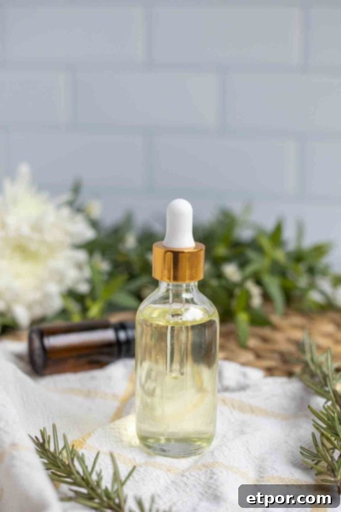 Boost Hair Growth with Homemade Rosemary Oil 4 a glass bottle with dropper full of castor oil infused with rosemary on a white and yellow towel surrounded by florals and rosemary