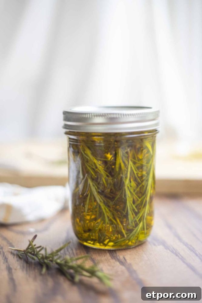 Boost Hair Growth with Homemade Rosemary Oil 7 fresh rosemary sprigs in oil in a mason jar on a wood countertop