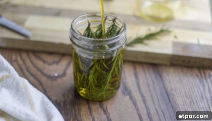 Boost Hair Growth with Homemade Rosemary Oil 9 olive oil poured rosemary in a mason jar on a wood countertop