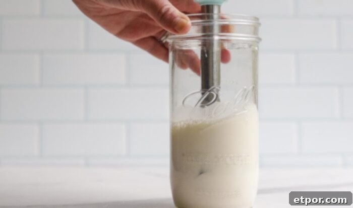 frothed milk that has doubled in size in a jar with a immersion blender.