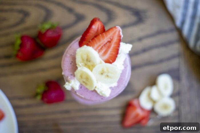 A simple, healthy strawberry banana milkshake in a mason jar, perfectly blended and ready to enjoy. A cream-colored towel is draped in the soft background.