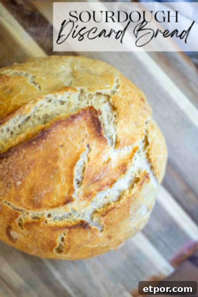 overhead photo of a loaf of crusty sourdough discard bread on a wood cutting board