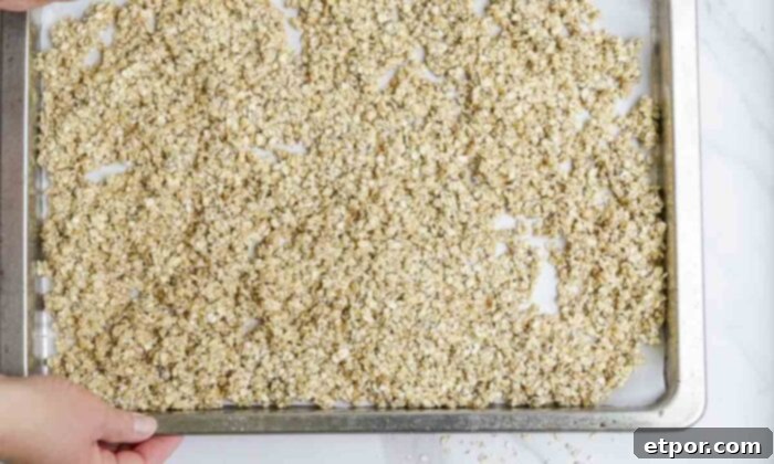 Unbaked granola spread on a parchment lined baking sheet.