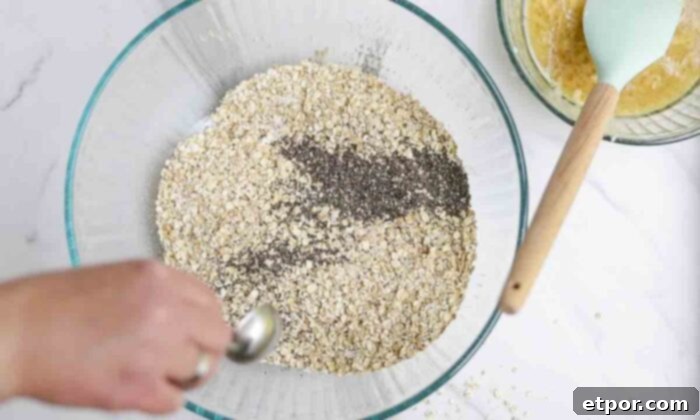 Chia seeds and oats in a large glass bowl on a white countertop.