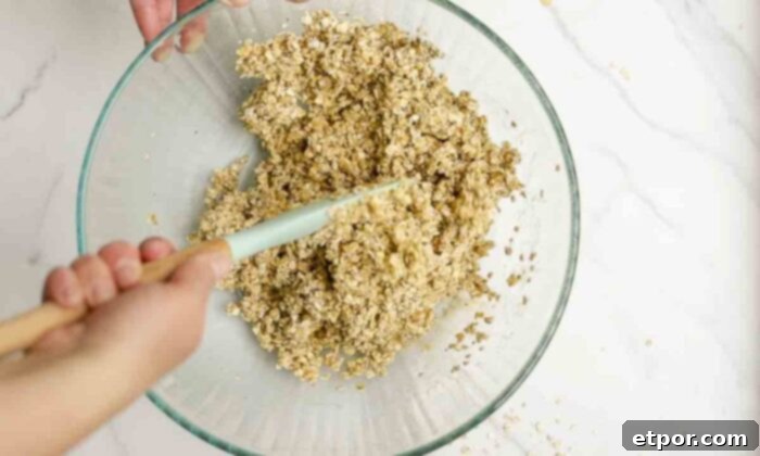 Oats in a large bowl being mixed together with starter, honey, and oil.