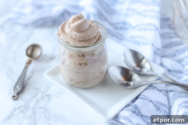 The Secret to Unforgettable Chocolate Whipped Cream 3 chocolate whipped cream in a glass container on a white plate with silver spoons