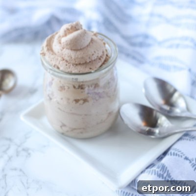 The Secret to Unforgettable Chocolate Whipped Cream 5 chocolate whipped cream in a glass container on a white plate with silver spoons