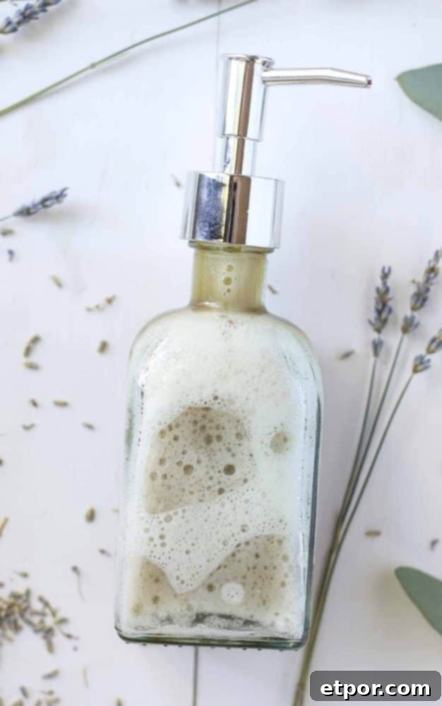 Close-up of a soap dispenser filled with DIY face wash on a white table with dried lavender surrounding the bottle, highlighting the natural ingredients.