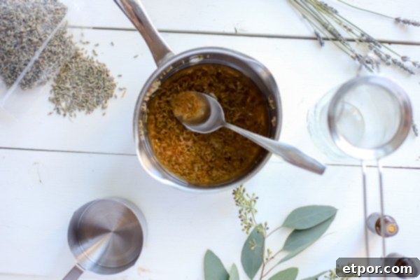 Lavender water for homemade face wash in a saucepan with herbs around it, showing the infusion process.