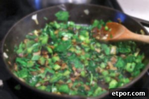 wilted spinach with green peppers and onions in a cast iron skillet for spinach frittata