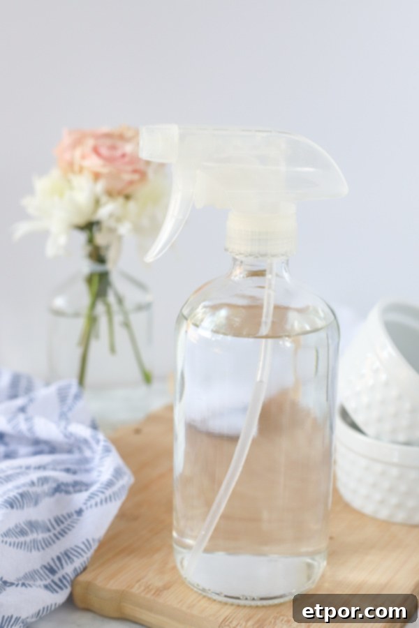 DIY glass cleaner in a glass bottle on a wood cutting board
