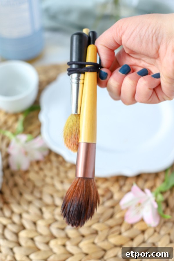 Natural Homemade Brush Wash 5 makeup brushes recently cleaned with DIY makeup brush cleaner tied together with a rubber-band and hung to dry