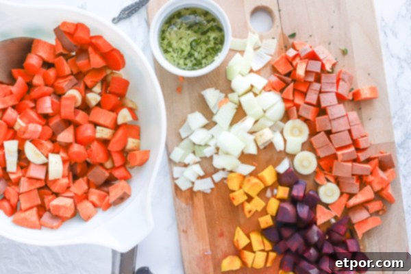 Rustic Roasted Root Vegetables 3 large bowl of chopped sweet potatoes next to a cutting board full of a variety of root vegetables for roasted root vegetables recipe preparation