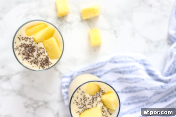 Guilt-Free Tropical Pina Colada Delight 4 two pina colada smoothies topped with chia seeds and pineapple on a blue and white napkin