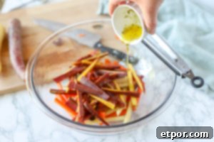 sliced carrots in a glass bowl with oil and herbs being poured on top