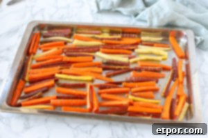 sliced carrots carefully placed onto baking sheet to bake into carrot fries