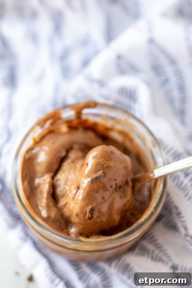 Chocolate Peanut Butter Banana Dream Freeze 9 A charming bowl of chocolate peanut butter banana nice cream in a glass jar, resting on a blue and white patterned napkin, ready to be enjoyed.