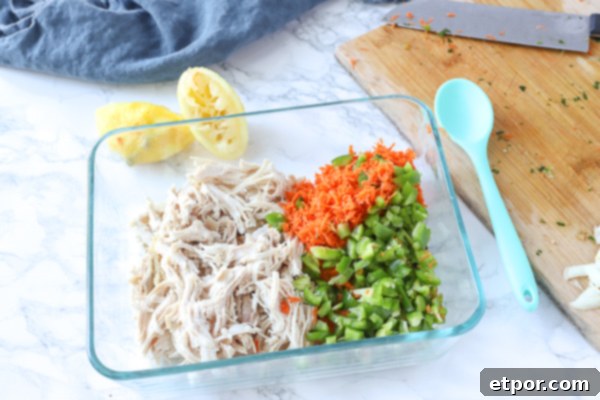 chicken, peppers, and carrots in glass bowl to make healthy chicken salad