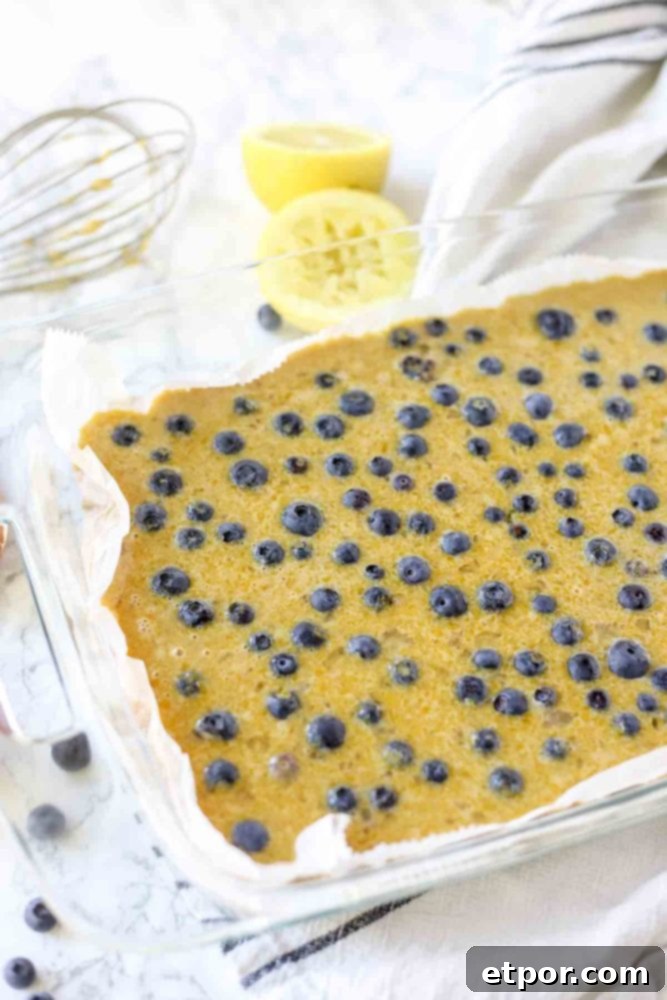 fresh blueberries sprinkled into lemon curd to make blueberry lemon bars.