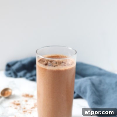 chocolate cauliflower smoothie in a glass cup with chocolate chips and cocoa powder around it