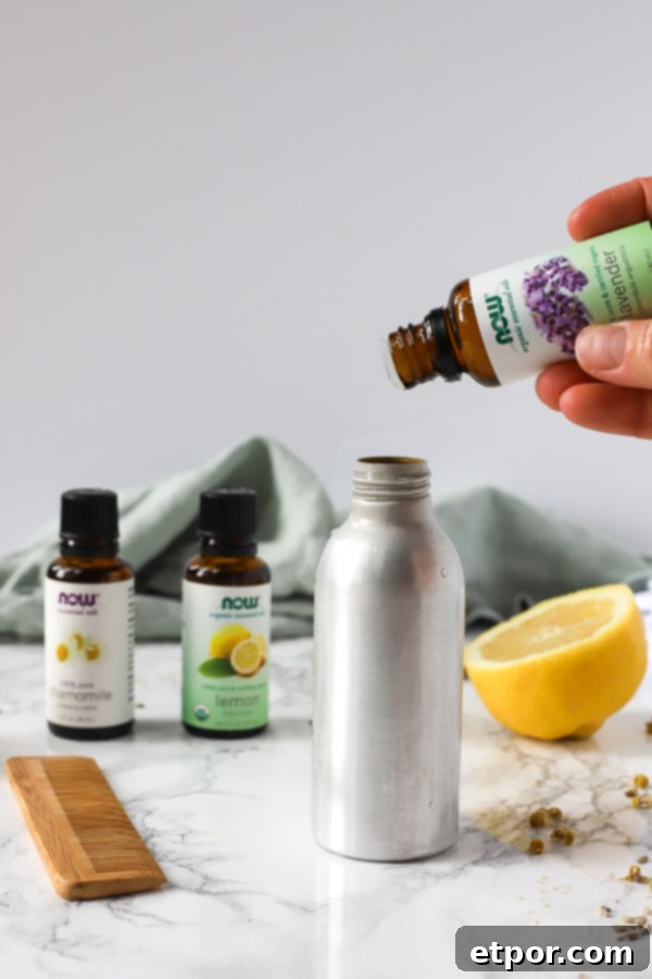 Adding essential oils to a metal spray bottle, part of the process of making homemade natural hair detangler.