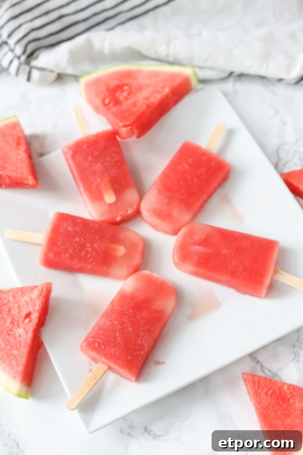 Refreshing Watermelon Pops 3 watermelon popsicles on white plate with watermelon slices around it