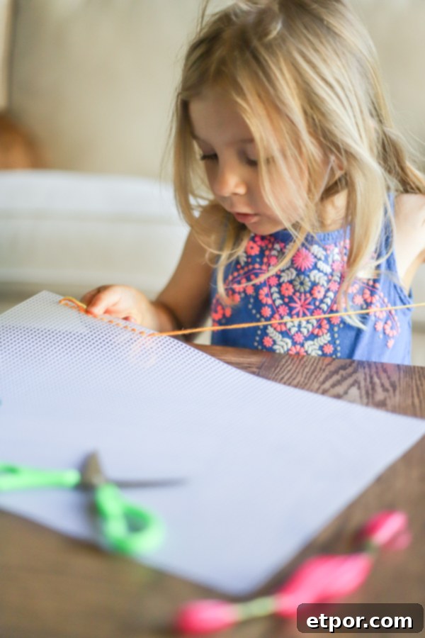 Child engaged in yarn threading activity, a great fine motor skill for winter activities.