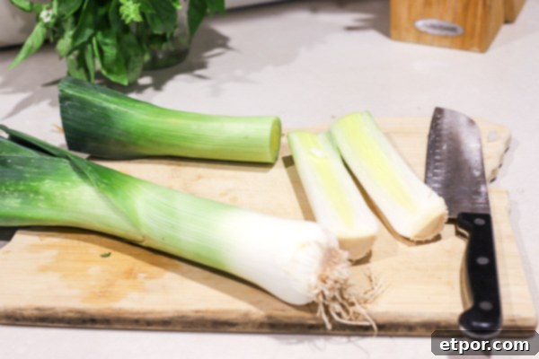 Wholesome Potato Leek Soup Vegan Friendly 4 A step-by-step image showing how to prepare leeks for potato leek soup on a cutting board with a knife, highlighting the cleaning and slicing process.