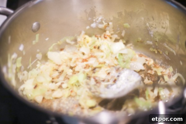 Wholesome Potato Leek Soup Vegan Friendly 5 Close-up shot of chopped leeks and onions gently sautéing in butter in a large soup pot, creating a fragrant base for the soup.