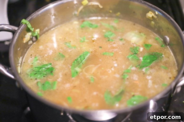 Wholesome Potato Leek Soup Vegan Friendly 6 A large soup pot on the stovetop, filled with the delicious potato leek soup simmering gently, with potatoes and herbs visible.
