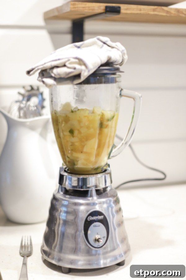 Wholesome Potato Leek Soup Vegan Friendly 7 A blender on a white countertop, half-filled with creamy potato leek soup, ready to be pureed to a smooth consistency.