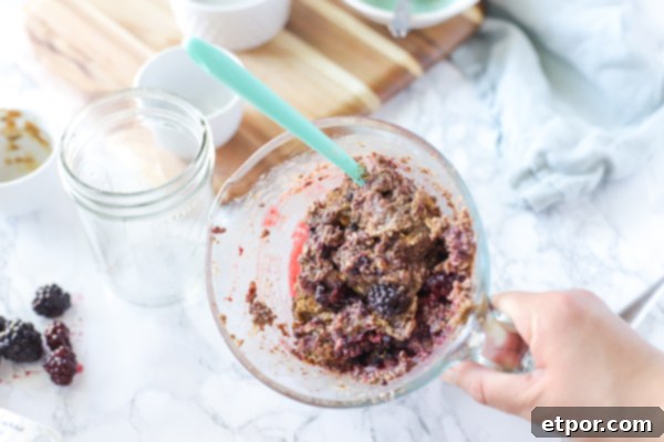 Power-Packed Blackberry Protein Cookies 4 Blue spoon mixing in frozen blackberries into a pyrex measuring cup