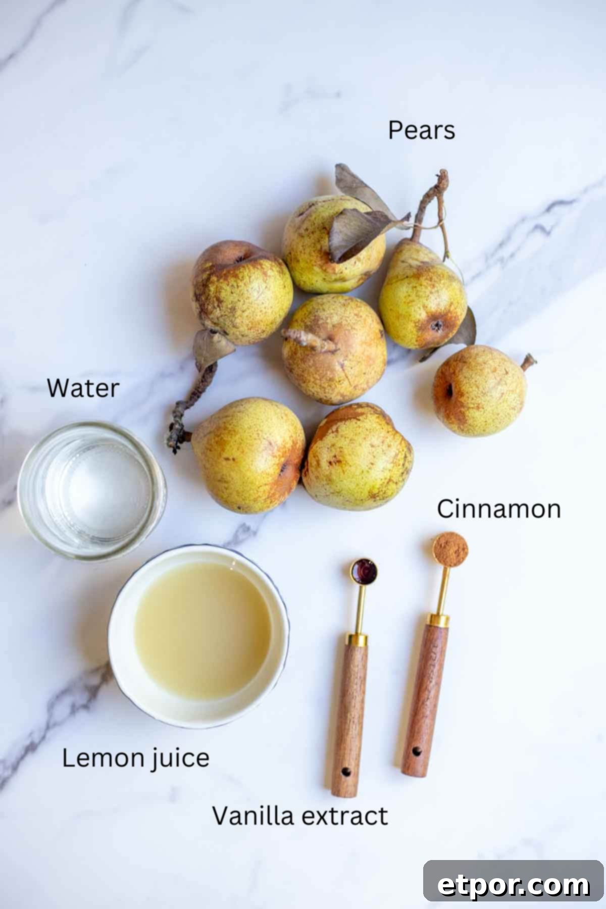 Pears, water, lemon juice, and measuring spoons of vanilla and cinnamon on a countertop.