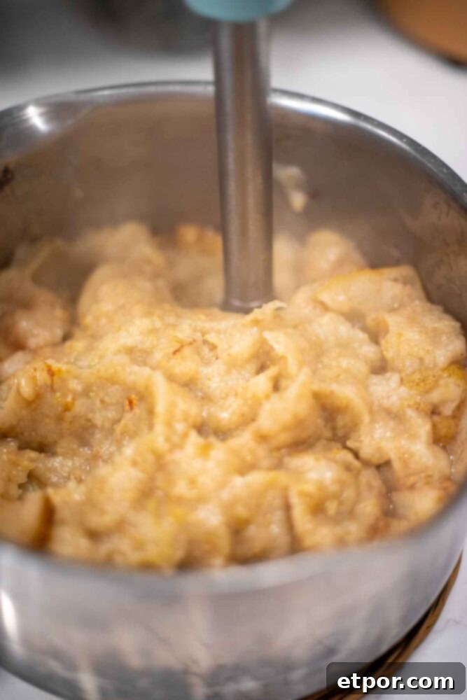 Blending pears in a pot with an immersion blender.
