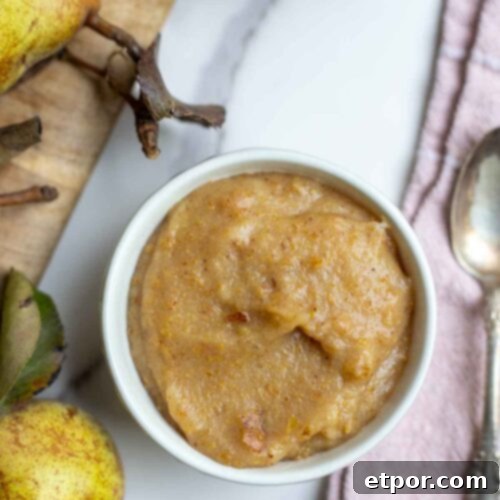 Pear sauce in a small bowl next to a cutting board with more pairs.